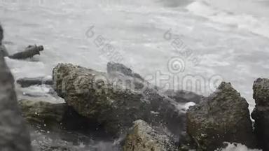 海浪拍打着岩石，里海的海浪拍打着海滩上的一座岩石和古老的金属建筑